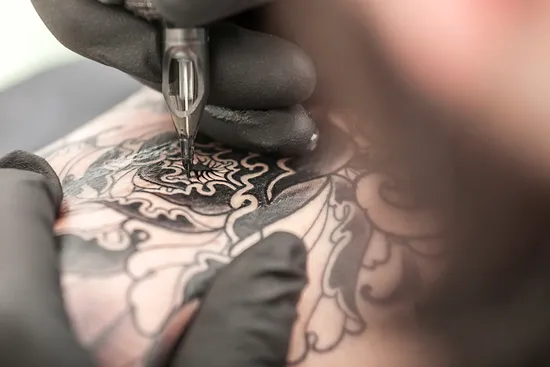 photo of tattooist drawing on arm of client